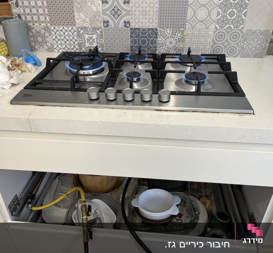 כיריים גז עם להבות כחולות ומגירות פתוחות מתחת